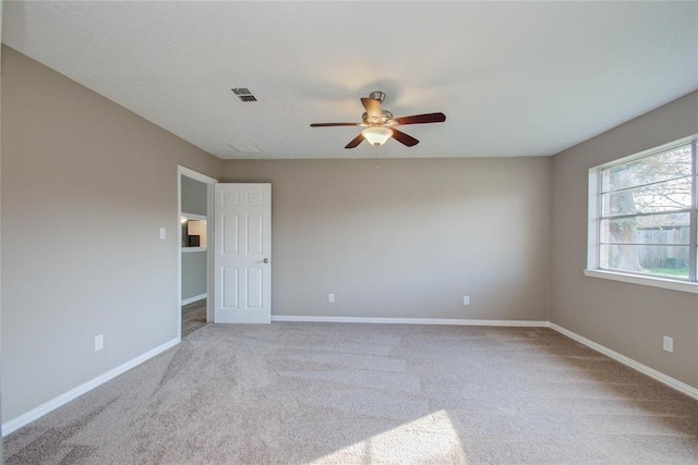 empty room with carpet floors, visible vents, ceiling fan, and baseboards