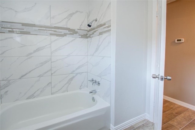 full bath with wood tiled floor, baseboards, and shower / washtub combination