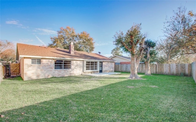 rear view of house featuring a fenced backyard, a yard, and brick siding