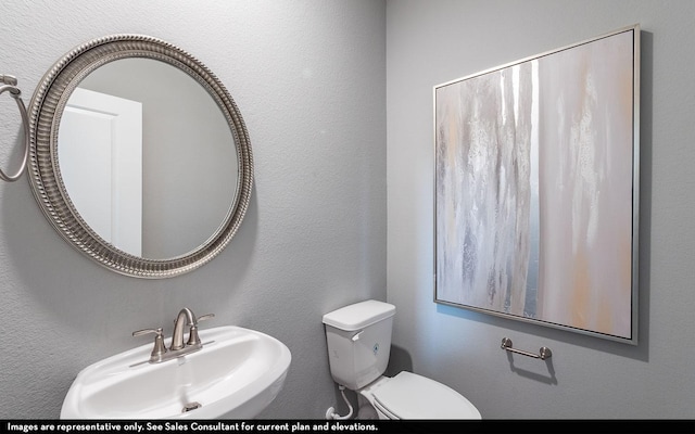 bathroom featuring a textured wall, a sink, and toilet