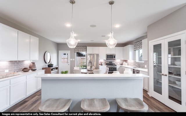 kitchen featuring stainless steel appliances, dark wood finished floors, a kitchen island, and white cabinetry