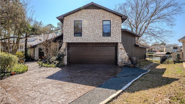 view of front of property with concrete driveway, stone siding, an attached garage, fence, and board and batten siding