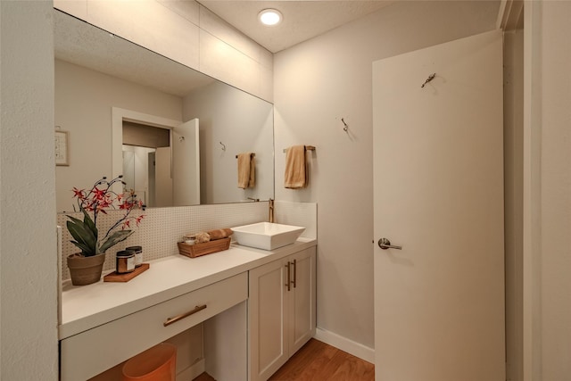 bathroom with baseboards, vanity, decorative backsplash, and wood finished floors