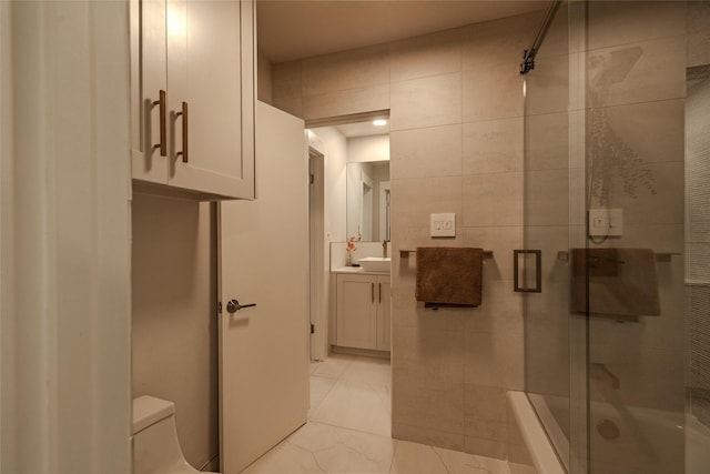 bathroom with toilet, tile walls, vanity, and an enclosed shower