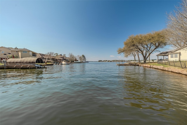 view of water feature featuring a dock, fence, and a residential view