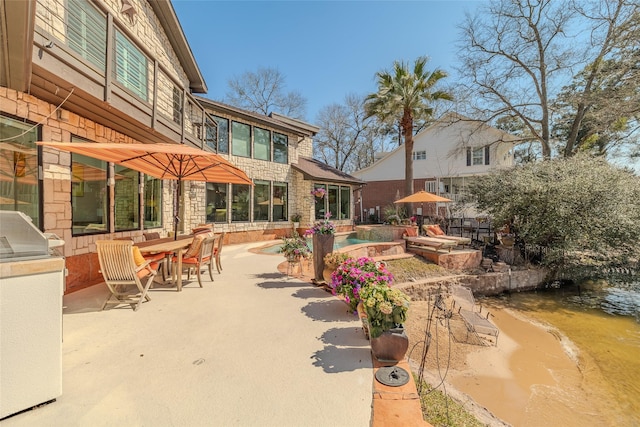 view of patio / terrace featuring exterior kitchen, outdoor dining space, and an outdoor pool