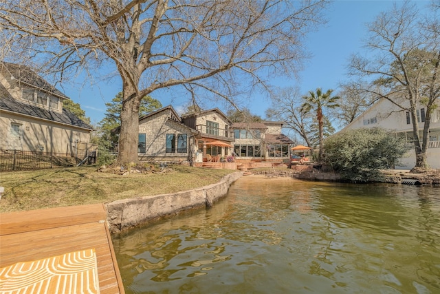 view of dock featuring a water view, fence, and a balcony