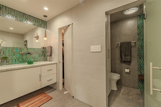 bathroom with toilet, vanity, tile walls, and tile patterned floors