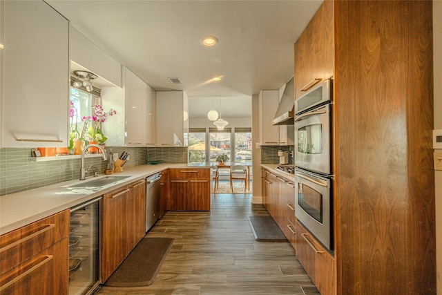 kitchen with modern cabinets, wine cooler, appliances with stainless steel finishes, brown cabinets, and a sink