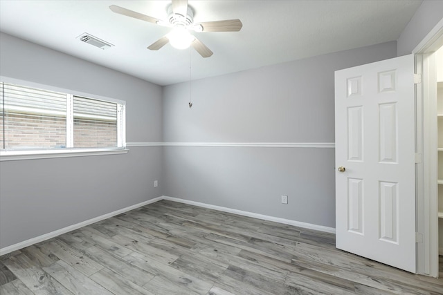 empty room with baseboards, visible vents, ceiling fan, and wood finished floors