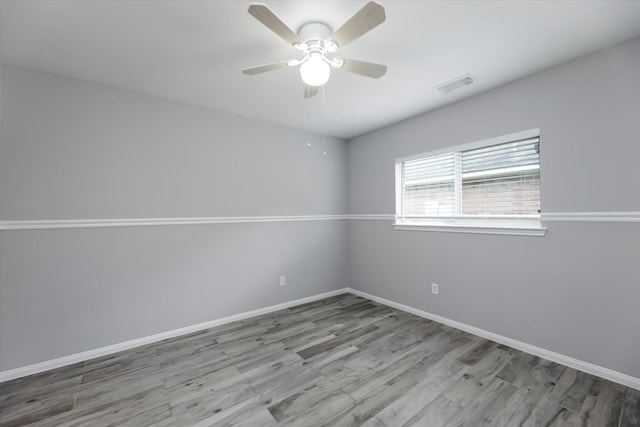 empty room with a ceiling fan, visible vents, baseboards, and wood finished floors