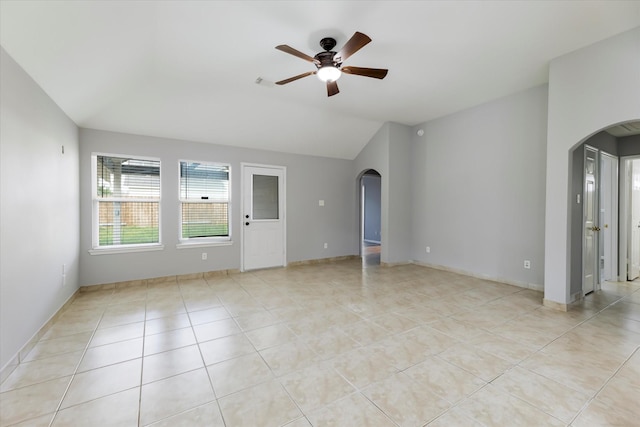 spare room with baseboards, arched walkways, a ceiling fan, lofted ceiling, and light tile patterned flooring