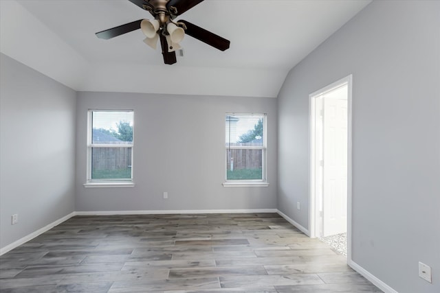 empty room featuring lofted ceiling, a healthy amount of sunlight, and wood finished floors