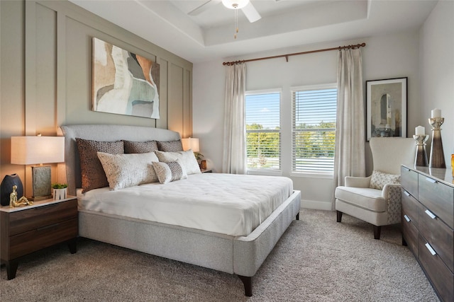 bedroom with baseboards, a tray ceiling, a ceiling fan, and light colored carpet