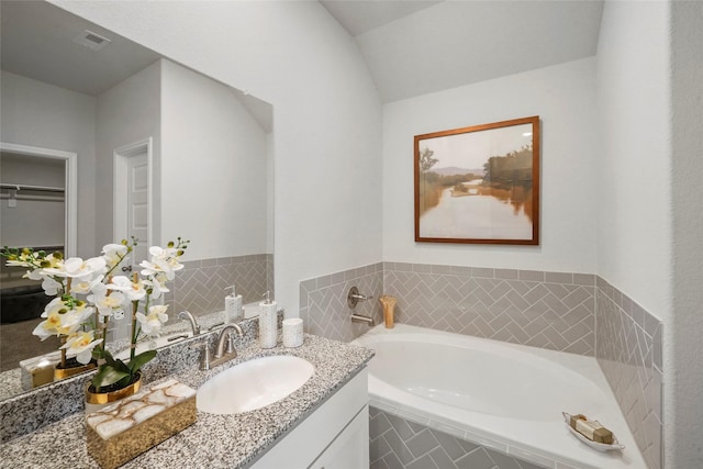 bathroom with a garden tub, visible vents, a walk in closet, and vanity