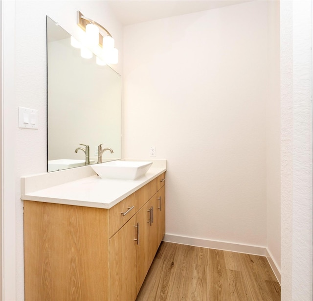 bathroom featuring baseboards, a chandelier, wood finished floors, and vanity