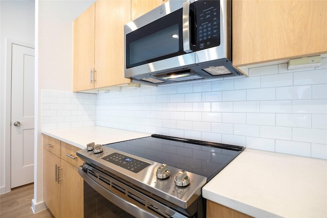 kitchen with stainless steel appliances, light brown cabinets, light countertops, and decorative backsplash