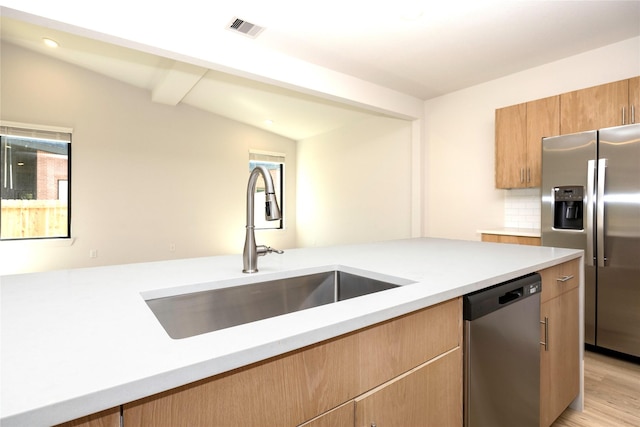 kitchen with stainless steel appliances, a sink, visible vents, light countertops, and backsplash