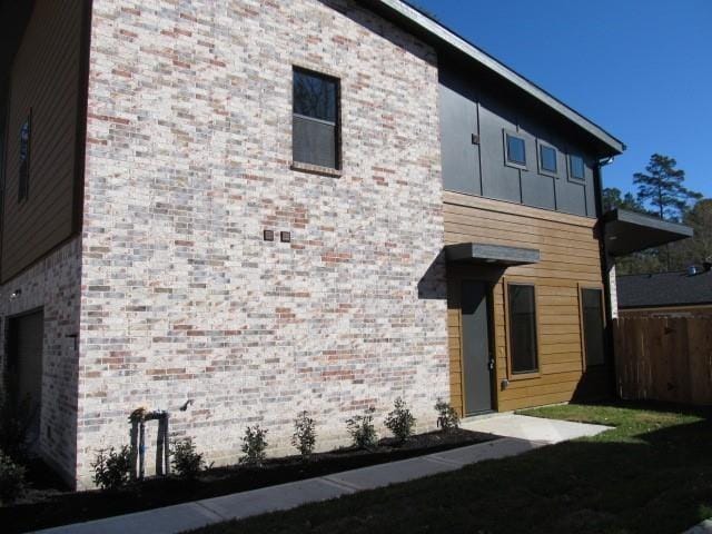 view of side of property featuring brick siding and fence