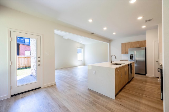 kitchen featuring visible vents, appliances with stainless steel finishes, brown cabinets, light wood-type flooring, and a sink