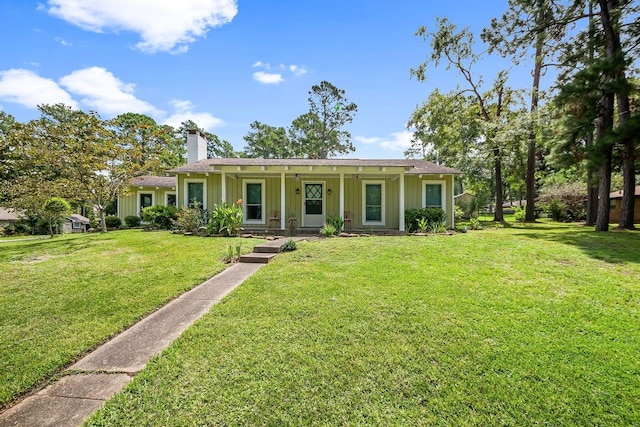 single story home with covered porch, a chimney, board and batten siding, and a front yard