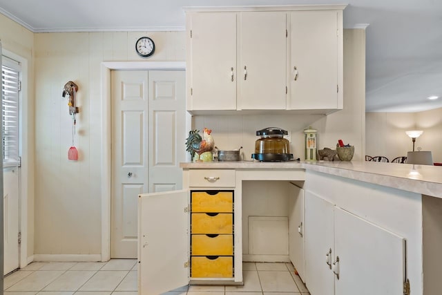 kitchen with white cabinets, decorative backsplash, light countertops, crown molding, and light tile patterned flooring