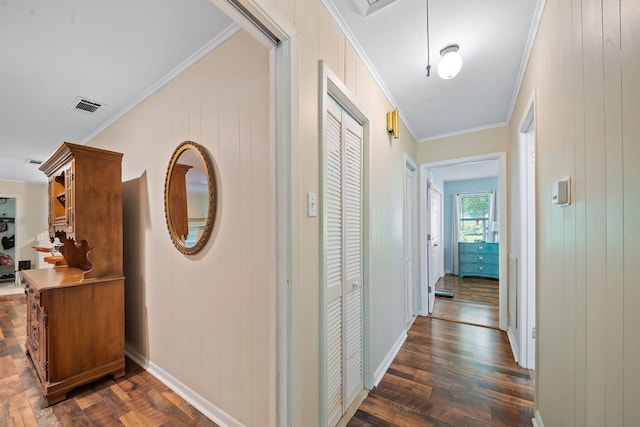 corridor featuring dark wood-style flooring, visible vents, crown molding, and baseboards