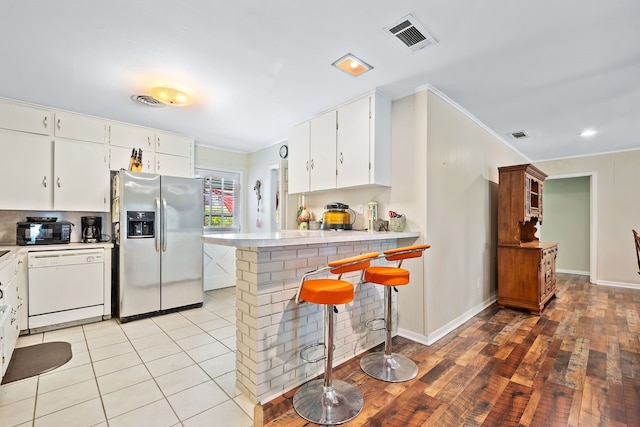 kitchen featuring visible vents, stainless steel fridge with ice dispenser, white dishwasher, light countertops, and crown molding