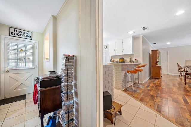 interior space featuring light tile patterned floors, recessed lighting, visible vents, baseboards, and ornamental molding