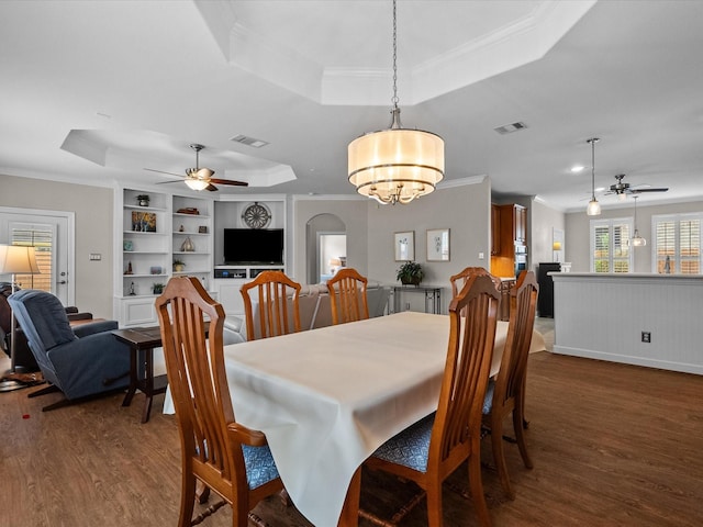 dining area featuring a tray ceiling, crown molding, visible vents, and dark wood-type flooring