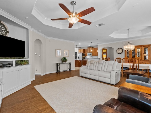 living room featuring a tray ceiling, arched walkways, dark wood-type flooring, and visible vents