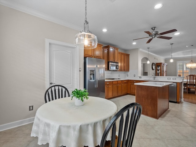 kitchen featuring a sink, appliances with stainless steel finishes, a peninsula, crown molding, and light countertops