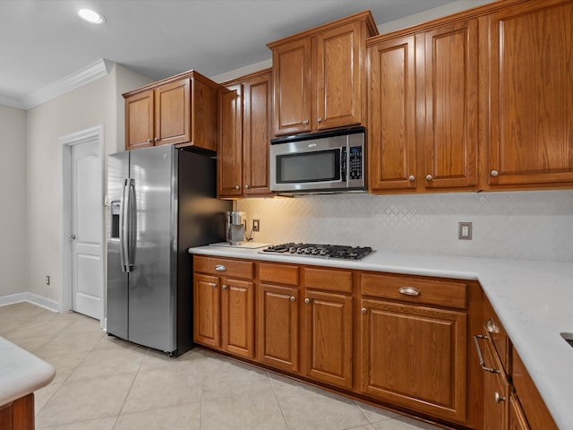 kitchen featuring light tile patterned floors, appliances with stainless steel finishes, crown molding, brown cabinets, and backsplash