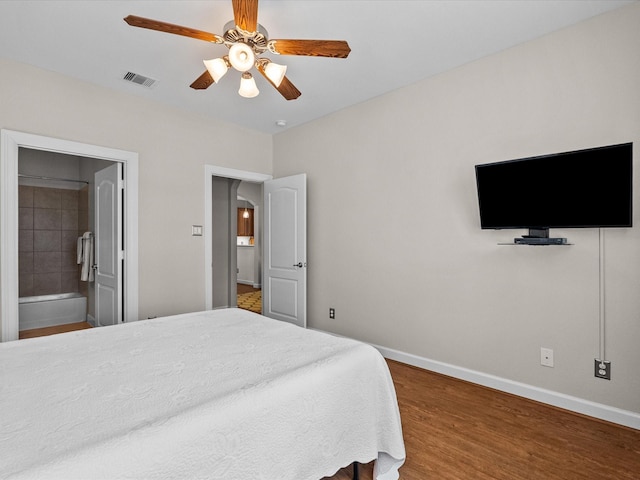 bedroom featuring visible vents, ensuite bathroom, a ceiling fan, wood finished floors, and baseboards