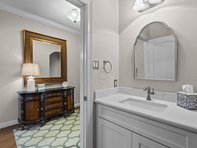 bathroom with vanity, wood finished floors, baseboards, and ornamental molding