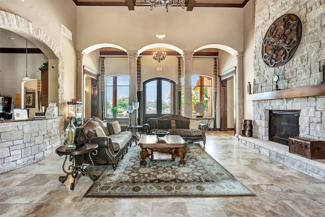 living area with visible vents, ornamental molding, a high ceiling, a fireplace, and decorative columns