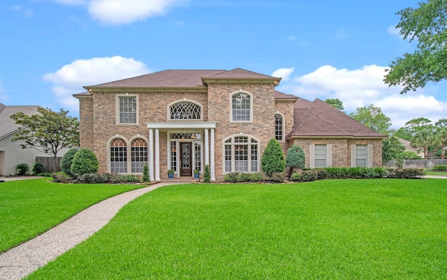 view of front of house with a front lawn, fence, and brick siding