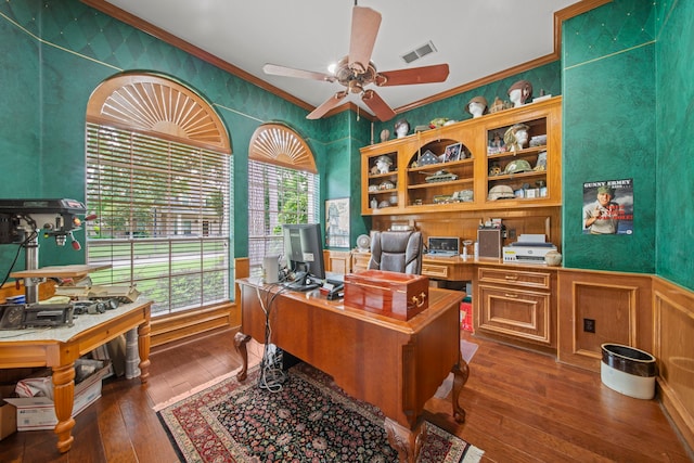 home office featuring dark wood finished floors, a ceiling fan, visible vents, and ornamental molding