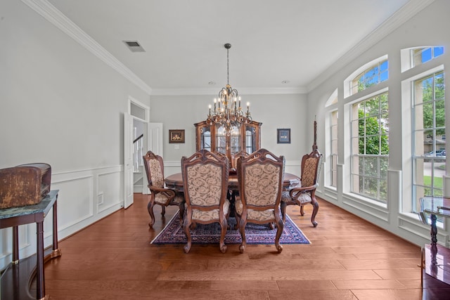 dining space featuring visible vents, a notable chandelier, wood finished floors, and crown molding