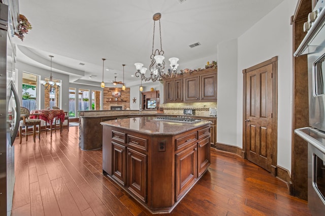 kitchen with visible vents, stainless steel appliances, a notable chandelier, backsplash, and a large fireplace