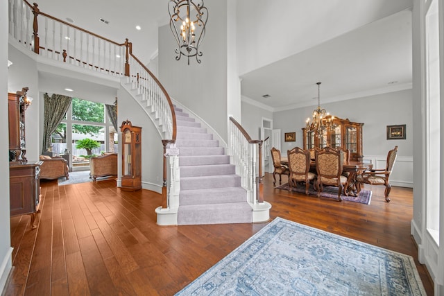 entrance foyer with an inviting chandelier, stairway, wood-type flooring, and ornamental molding