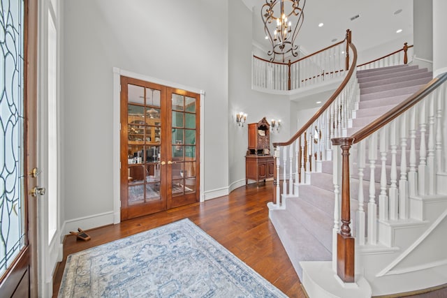 foyer entrance featuring a notable chandelier, hardwood / wood-style flooring, french doors, baseboards, and stairs