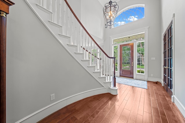 entryway featuring stairs, a high ceiling, wood finished floors, and a chandelier