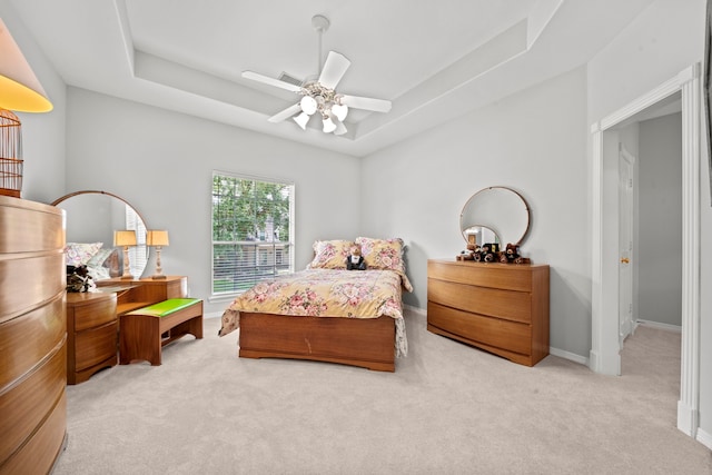 bedroom featuring ceiling fan, baseboards, a raised ceiling, and carpet