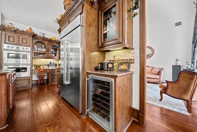 bar with dark wood-type flooring, wine cooler, visible vents, and stainless steel appliances