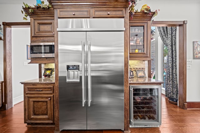 kitchen featuring glass insert cabinets, appliances with stainless steel finishes, beverage cooler, and dark wood finished floors