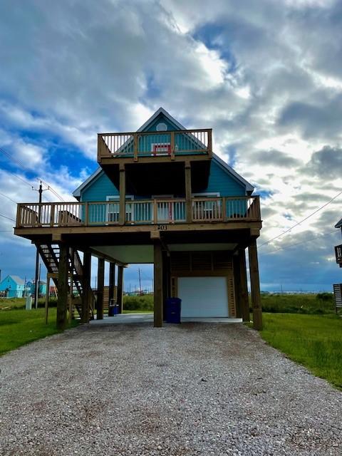 view of front of house with an attached garage, a carport, gravel driveway, and stairs