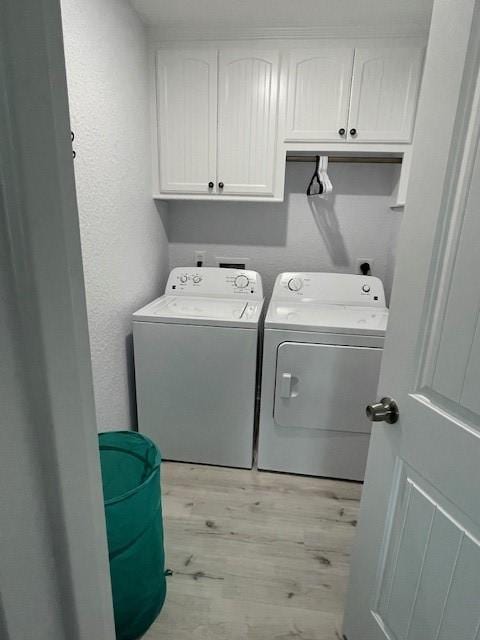 203 Sea Oats Dr, Surfside Beach, TX 77541 - clothes washing area featuring cabinet space, a textured wall, light wood-style floors, and independent washer and dryer