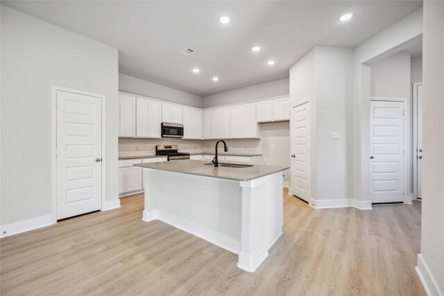 kitchen with a sink, appliances with stainless steel finishes, light wood-style flooring, and white cabinetry