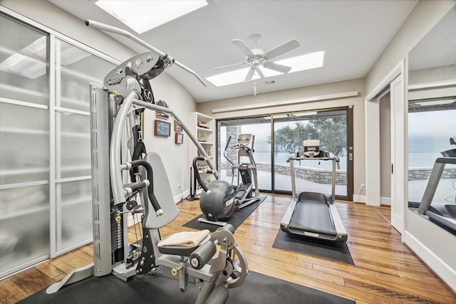 exercise room featuring a skylight, baseboards, a ceiling fan, and wood finished floors